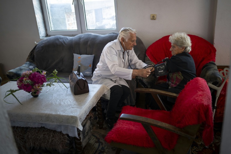 Le docteur Apostolov, médecin généraliste de 90 ans, mesure la tension d'une patiente dans le village de Skrat, situé au pied du massif de la Belassitsa en Bulgarie, le 15 juillet 2026