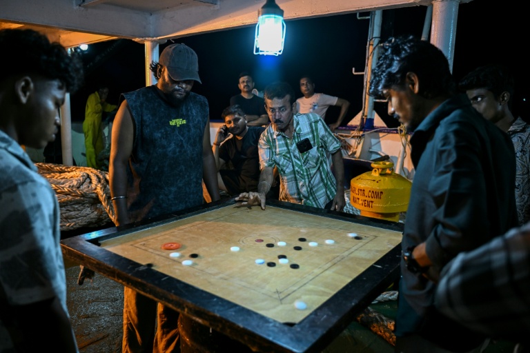 Des passagers jouent au carom à bord du ferry Kalighat, l'unique lien entre Chowra et Car Nicobar, deux minuscules morceaux de l'archipel indien des Andaman-et-Nicobar, en plein cœur de l'océan Indien, le 30 mars 2026