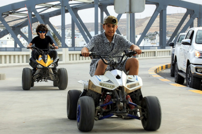 Des enfants sur des quads le long du trottoir piétonnier d'une route surplombant le front de mer de la ville de Derna, dans l'est de la Libye, le 15 mai 2026, après les efforts de reconstruction qui ont suivi tempête Daniel