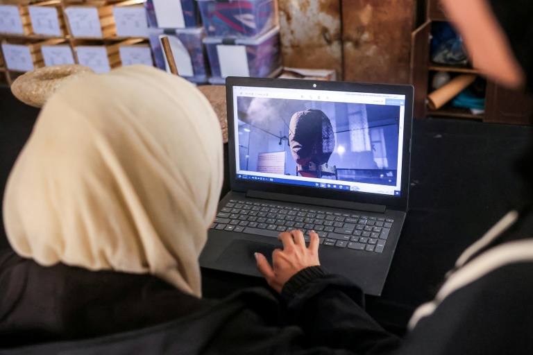 Une membre de l'association Mayasem pour la culture et les arts examine des images sur un ordinateur portable,au centre de stockage du patrimoine culturel à Khan Younès, le 11 juillet 2026 dans le sud de la bande de Gaza