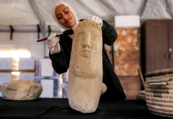 Une membre de l'association Mayasem pour la culture et les arts nettoie un artefact à la brosse, sous une tente à Khan Younès, dans le sud de la bande de Gaza, le 11 juillet 2026
