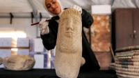 Une membre de l'association Mayasem pour la culture et les arts nettoie un artefact à la brosse, sous une tente à Khan Younès, dans le sud de la bande de Gaza, le 11 juillet 2026
