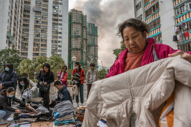 Des habitants trient des vêtements qui leur ont été donnés après qu'un important incendie a ravagé plusieurs immeubles d'appartements du complexe résidentiel Wang Fuk Court à Hong Kong, le 27 novembre 2025

