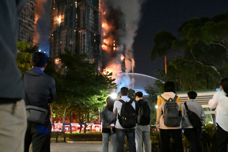 Des personnes observent l'incendie qui s'est déclaré dans le complexe résidentiel Wang Fuk Court, dans le quartier de Tai Po, le 26 novembre 2025 à Hong Kong