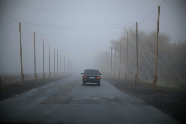 Une voiture roule sur une route protégée par des filets antidrones, près de Kramatorsk, dans l'est de l'Ukraine, le 10 octobre 2025 
