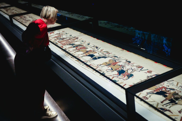 Une femme se penche pour observer la Tapisserie de Bayeux lors d'une avant-première réservée à la presse, organisée en amont de l'inauguration officielle au British Museum, dans le centre de Londres, le 7 septembre 2026