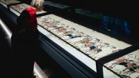 Une femme se penche pour observer la Tapisserie de Bayeux lors d'une avant-première réservée à la presse, organisée en amont de l'inauguration officielle au British Museum, dans le centre de Londres, le 7 septembre 2026