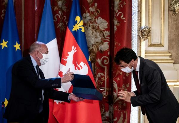 L'écologiste Grégory Doucet (d) reçoit l'écharpe de maire des mains du maire sortant et ancien ministre de l'Intérieur Gérard Collomb (g), le 4 juillet 2020