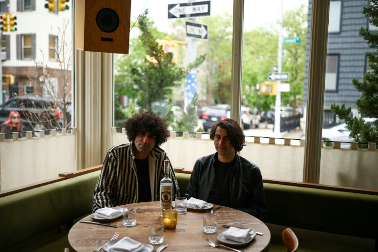 Siavash Karampour (à gauche) et Sasan Oskouei (à droite) posent avec une bouteille de leur eau-de-vie traditionnelle iranienne, l'aragh sagi, dans un restaurant de Brooklyn à New York, le 28 avril 2026