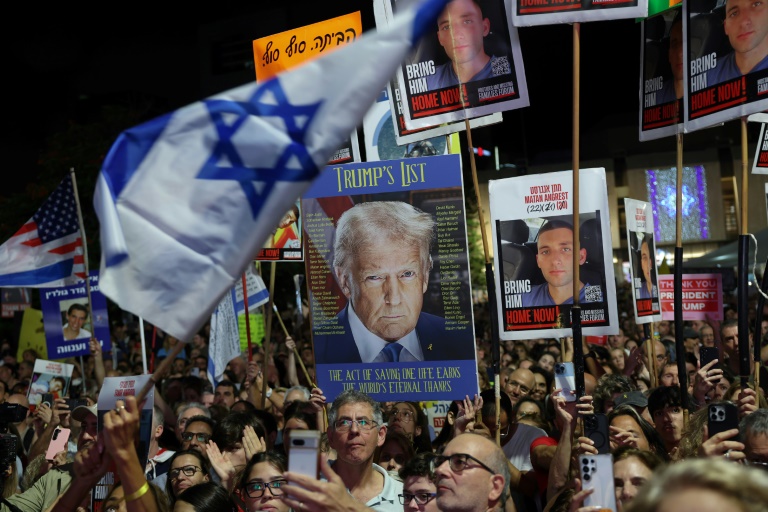 Des manifestants brandissent des drapeaux israéliens et américains, ainsi que des photos d'otages retenus à Gaza,  lors d’un rassemblement à Tel-Aviv, le 11 octobre 2025