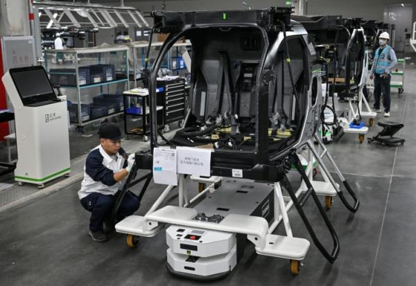 Des employés travaillent sur une chaîne de montage pour la voiture volante électrique "Land Aircraft Carrier" dans une usine de la filiale Aridge de Xpeng à Guangzhou, dans le sud de la Chine, le 6 novembre 2025