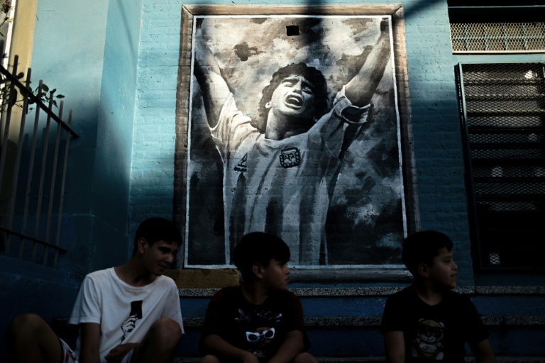 Des enfants devant une fresque murale représentant la star de football Diego Maradona, aujourd’hui décédé, dans son quartier natal de Villa Fiorito, dans la province de Buenos Aires, en Argentine, le 9 avril 2026