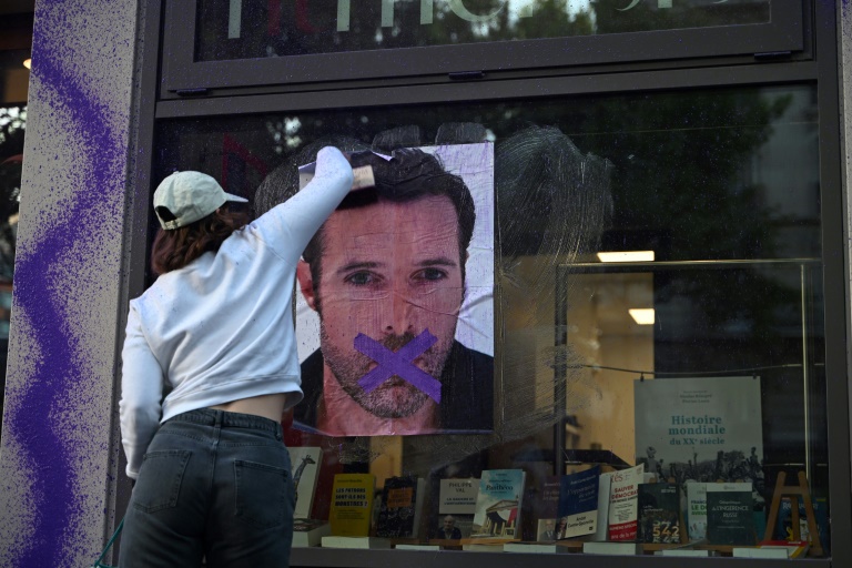 Une militante féministe colle une affiche dénonçant la publication d'un livre de Nicolas Bedos, condamné en octobre pour agressions sexuelles, le 23 mai 2025 à Paris