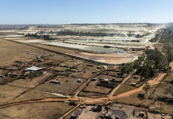 Vue aérienne de parcelles agricoles et de talus miniers en arrière-plan, dans le quartier de Snake Park, à Soweto, le 30 mai 2025 en Afrique du Sud