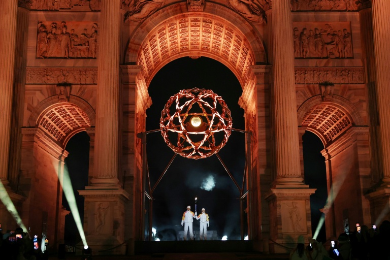 Les légendes italiennes du ski Deborah Compagnoni et Alberto Tomba allument la vasque olympique sous l'Arc de la paix à Milan, lors de la cérémonie d'ouverture des Jeux de Milan Cortina, le 6 février 2026
