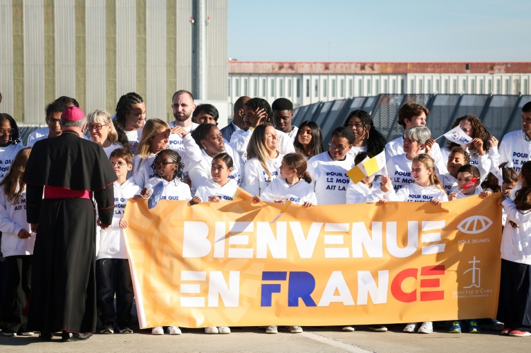 Des personnes se tiennent derrière une banderole sur laquelle on peut lire 