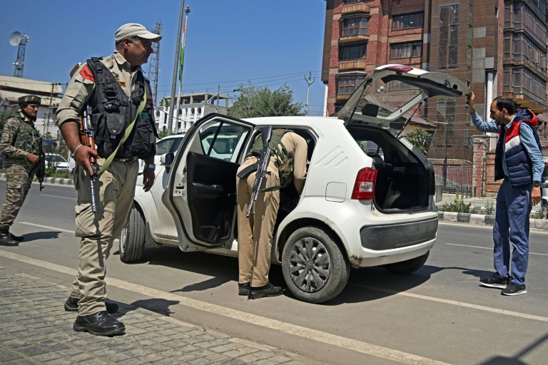 Des paramilitaires indiens montent la garde pendant qu'un policier inspecte un véhicule dans une rue de Srinagar, le 30 avril 2025 au Cachemire indien