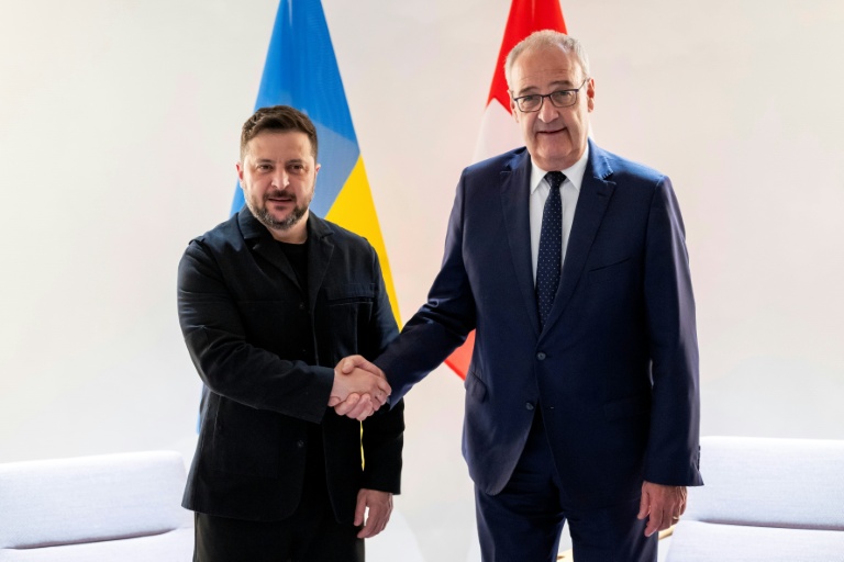 Le président suisse Guy Parmelin (d.) serre la main du président ukrainien Volodymyr Zelensky avant une rencontre bilatérale en marge du sommet du G7, à l'aéroport de Genève, le 15 juin 2026