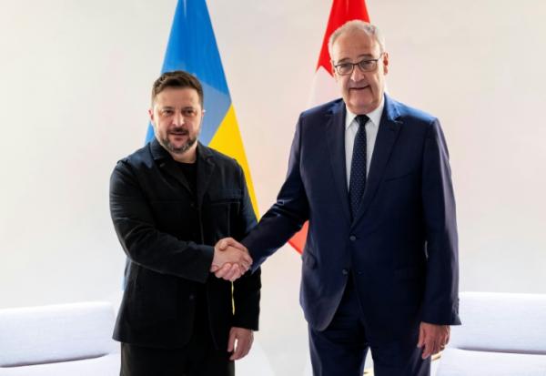 Le président suisse Guy Parmelin (d.) serre la main du président ukrainien Volodymyr Zelensky avant une rencontre bilatérale en marge du sommet du G7, à l'aéroport de Genève, le 15 juin 2026