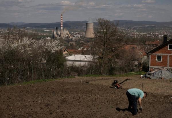 Un homme travaille dans son jardin qui surplombe une centrale thermique au charbon, près de la ville d'Obilic, au Kosovo, le 10 avril 2026