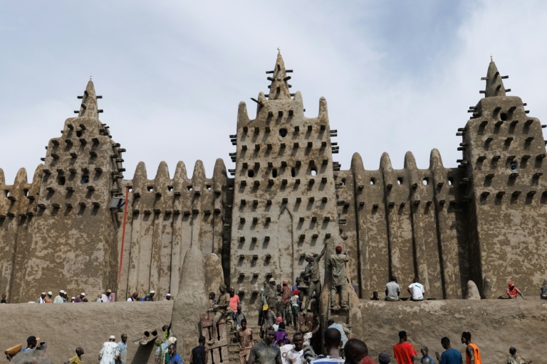 Des personnes utilisent du banco, un enduit de terre, pour le crépissage annuel de la grande mosquée de Djenné le 12 juin 2025