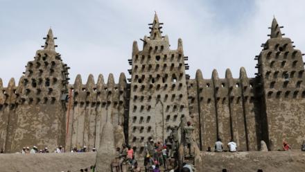 Des personnes utilisent du banco, un enduit de terre, pour le crépissage annuel de la grande mosquée de Djenné le 12 juin 2025