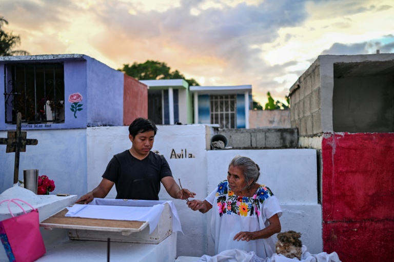 Un jeune accompagné de sa grand-mère se prépare à nettoyer les restes d'un proche avant les célébrations du Jour des Morts au cimetière de Pomuch, dans l'État de Campeche, au Mexique, le 18 octobre 202
