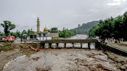 Des villageois (d) se tiennent près d'un pont alors que le niveau des eaux de crue monte dans le district de Buner, dans la province  de Khyber Pakhtunkhwa, le 18 août 2025 au Pakistan