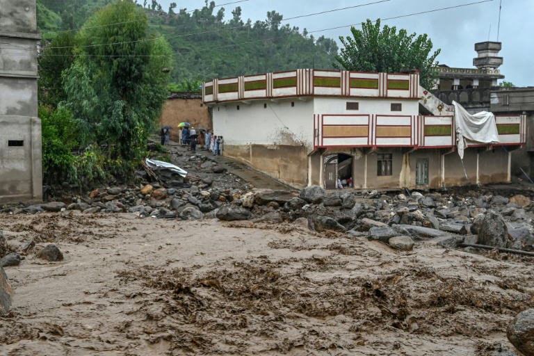 Des villageois (c) près d'un bâtiment alors que le niveau des eaux de crue monte dans le district de Buner, dans la province de Khyber Pakhtunkhwa, le 18 août 2025 au Pakistan