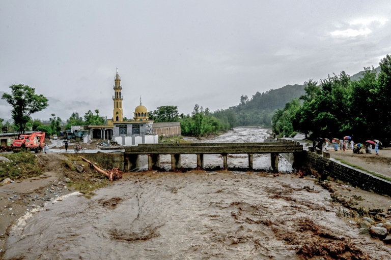 Des villageois (d) se tiennent près d'un pont alors que le niveau des eaux de crue monte dans le district de Buner, dans la province de Khyber Pakhtunkhwa, le 18 août 2025 au Pakistan