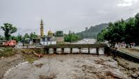 Des villageois (d) se tiennent près d'un pont alors que le niveau des eaux de crue monte dans le district de Buner, dans la province  de Khyber Pakhtunkhwa, le 18 août 2025 au Pakistan