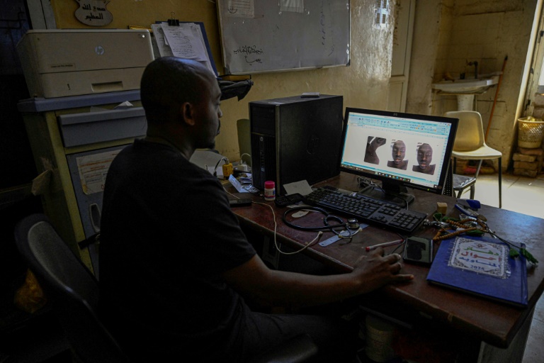 Un bénévole soudanais chargé des procédures d’inhumation des corps non identifiés à Khartoum examine des photos d’une victime à l’hôpital Al-Nao d’Omdourman, le 18 avril 2026