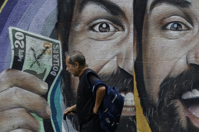 Un habitant passe devant une fresque murale liée aux taux de change à Caracas, au Venezuela, le 2 juin 2025