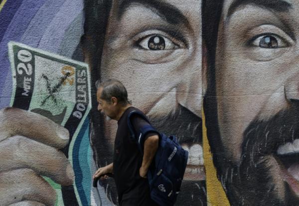 Un habitant passe devant une fresque murale liée aux taux de change à Caracas, au Venezuela, le 2 juin 2025
