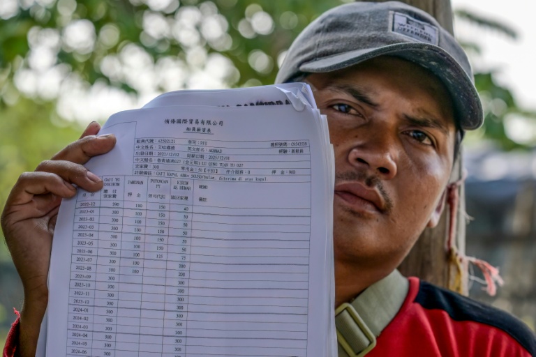 Akhmad, ancien membre d'équipage d'un navire de pêche chinois, montre son contrat et son salaire mensuel lors d'un entretien avec l'AFP au port du hameau de Bungko Lor, à Cirebon, le 10 juin 2026 en Indonésie