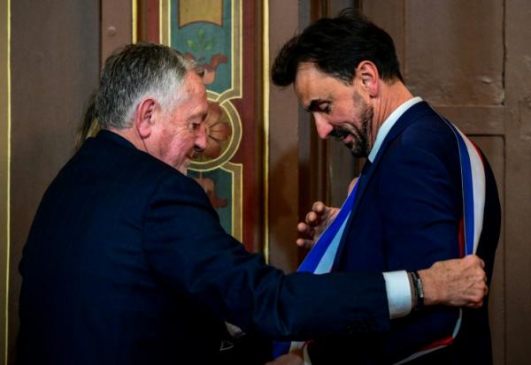 Le maire réélu Grégory Doucet, à droite, reçoit son écharpe des mains de Jean-Michel Aulas, à gauche, le 27 mars 2026, à Lyon