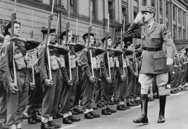 Le chef des Forces françaises libres (FFL), Charles de Gaulle, salue des marins alors qu'il passe en revue les troupes françaises lors du défilé militaire célébrant la fête nationale française à Londres, le 14 juillet 1942, durant la Seconde Guerre mondiale