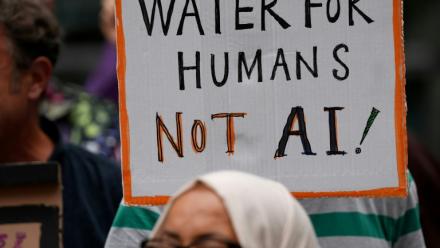 Une personne brandit une pancarte indiquant "De l'eau pour les humains, pas pour l'IA" lors d'une manifestation contre l'approbation d'un centre de données prévu dans les plans de réaménagement du quartier de Brick Lane, le 4 septembre 2026 à Londres