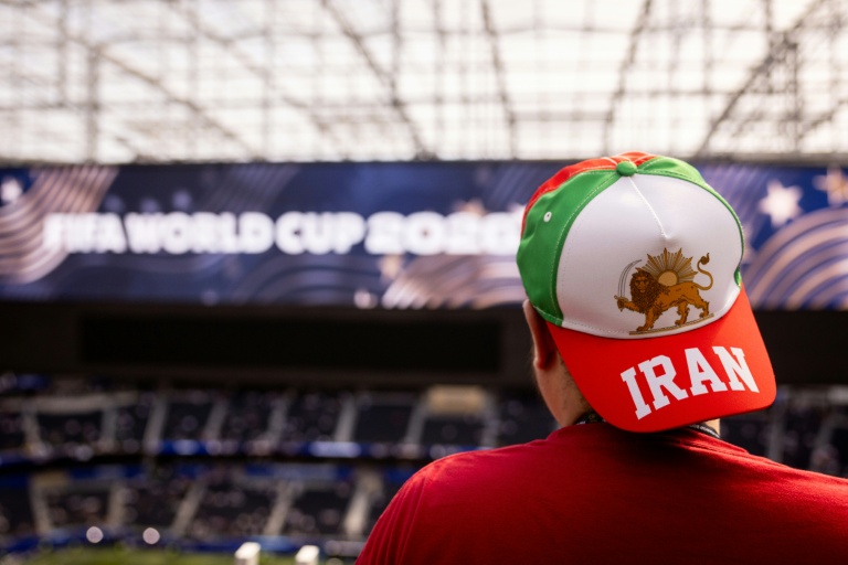 Un spectateur porte une casquette avec le drapeau utilisé par l'Iran avant la révolution islamique, et un drapeau israélien, à l'intérieur du SoFi Stadium à Inglewood, près de Los Angeles, le 15 juin 2026