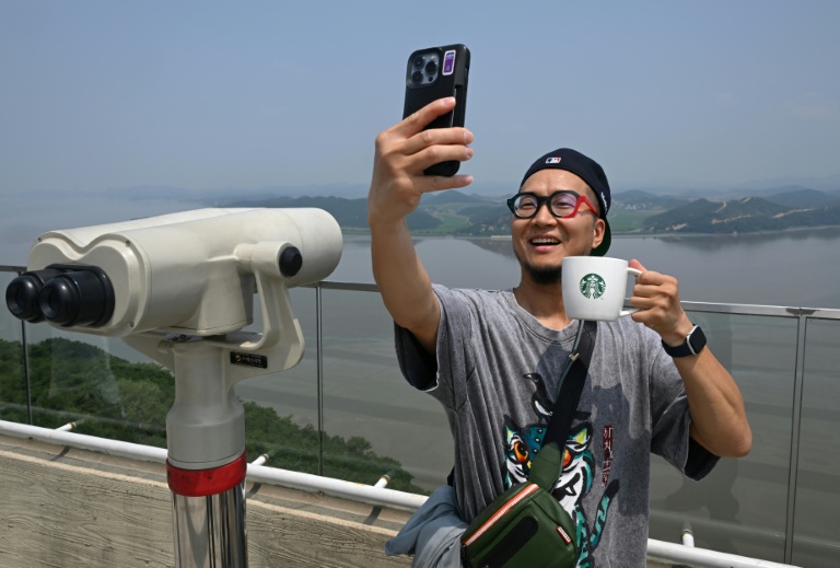 Un touriste prend un selfie avec une tasse Starbucks devant la Corée du Nord depuis une plate-forme d'observation sud-coréenne située à l'Écoparc de la Paix d'Aegibong, à Gimpo, le 1er juillet 2026 