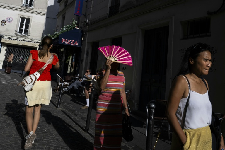 Une passante se protège du soleil avec un éventail à Montmartre, à Paris, le 12 août 2025, en pleine vague de chaleur