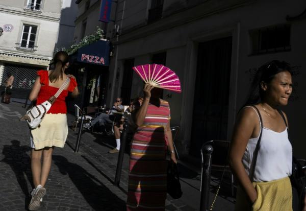 Une passante se protège du soleil avec un éventail à Montmartre, à Paris, le 12 août 2025, en pleine vague de chaleur