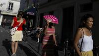 Une passante se protège du soleil avec un éventail à Montmartre, à Paris, le 12 août 2025, en pleine vague de chaleur