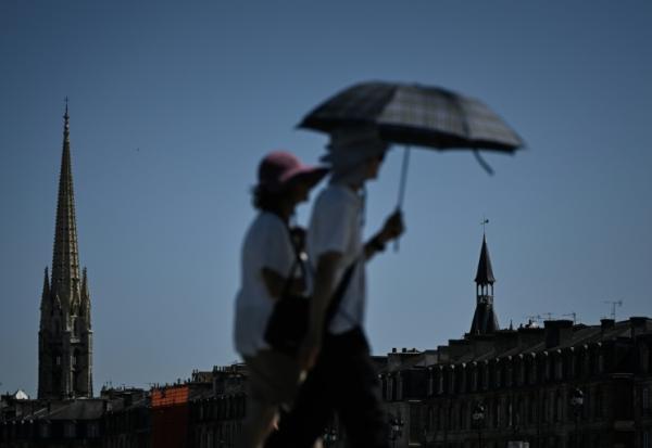Des passants se protègent de la chaleur avec un parapluie, le 6 juillet 2026 à Bordeaux 