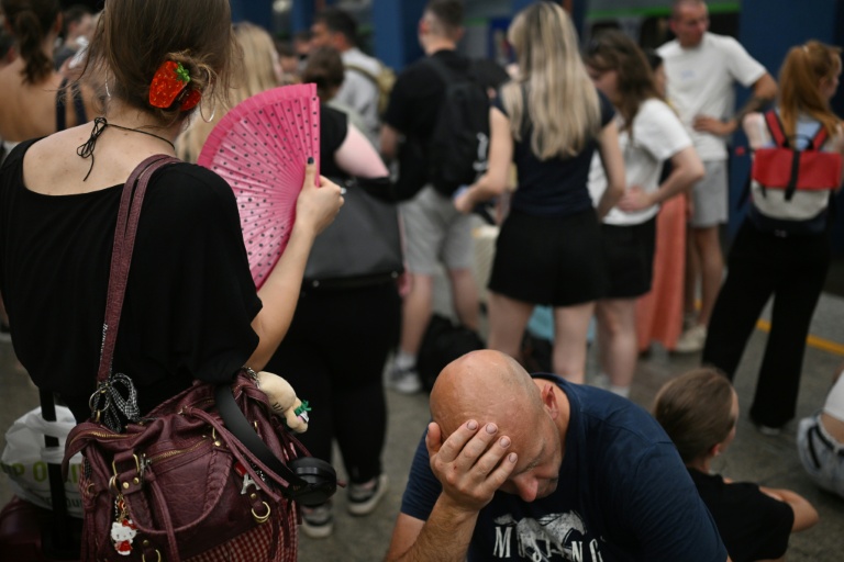 Des voyageurs attendent sur un quai de la gare centrale de Varsovie des trains retardés par la vague de chaleur, le 28 juin 2026 en Pologne
