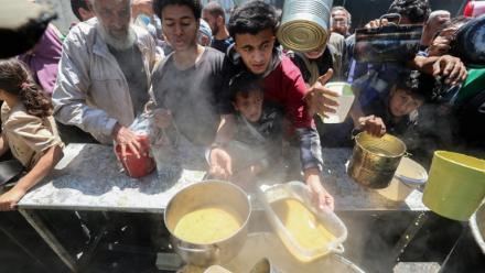 Des Palestiniens font la queue pour obtenir un repas chaud à une cuisine communautaire mise en place par le Programme alimentaire mondial (PAM), au camp de réfugiés de Nuseirat (Territoires palestiniens), dans le centre de la bande de Gaza, le 26 avril 2025