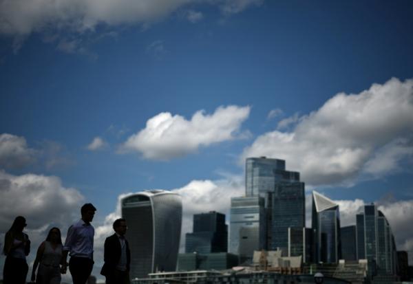 Des passants le long de la rive sud de la Tamise d'où l'on aperçoit le quartier des affaires et financier du centre de Londres, le 14 août 2025