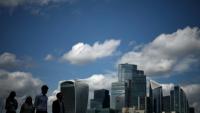 Des passants le long de la rive sud de la Tamise d'où l'on aperçoit le quartier des affaires et financier du centre de Londres, le 14 août 2025