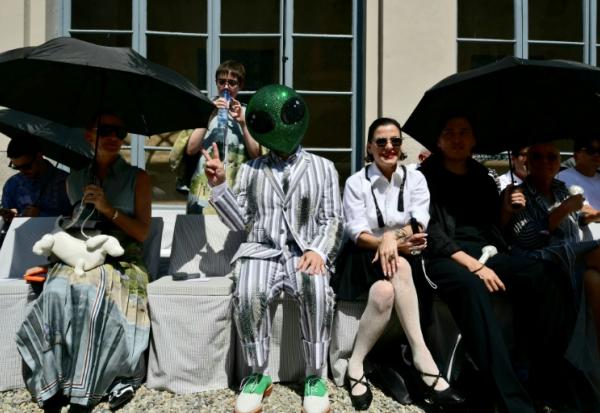 Un invité portant un masque d'extraterrestre assiste au défilé de la collection Thom Browne lors de la Fashion Week Homme Printemps/Été 2027 de Milan, à Milan, le 22 juin 2026