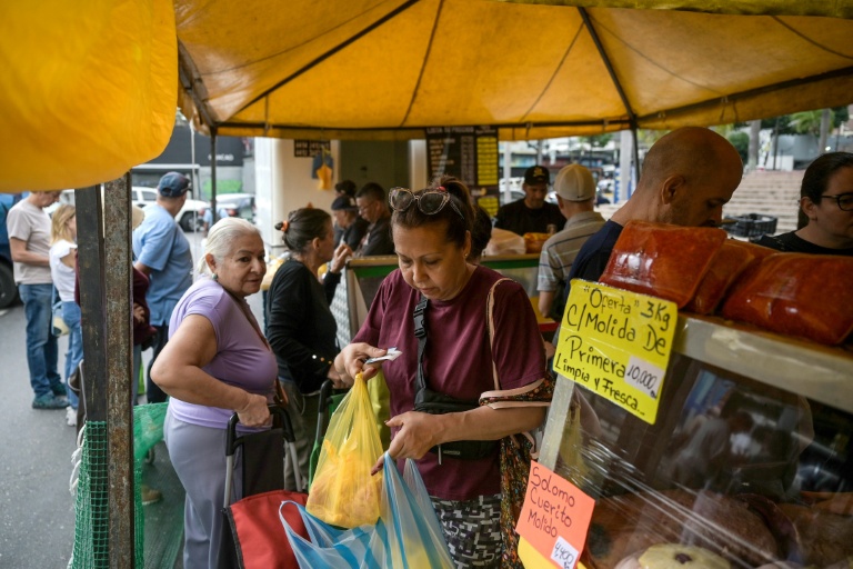 Des personnes font leurs courses sur un marché de rue à Caracas, le 20 décembre 2025 au Venezuela